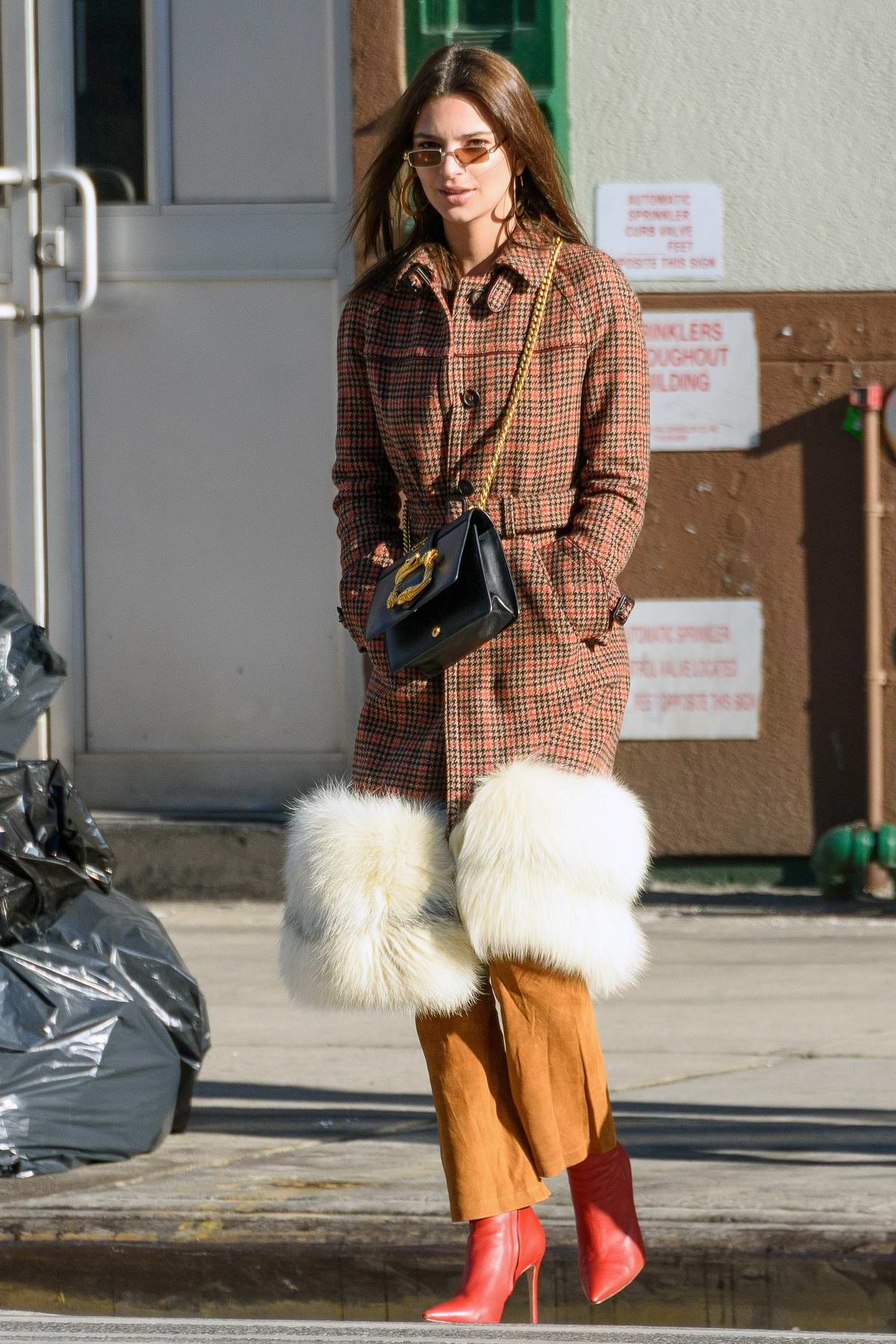 Emily Ratajkowski dressed in a stylish fur trimmed plaid jacket with red boots, spotted out with
