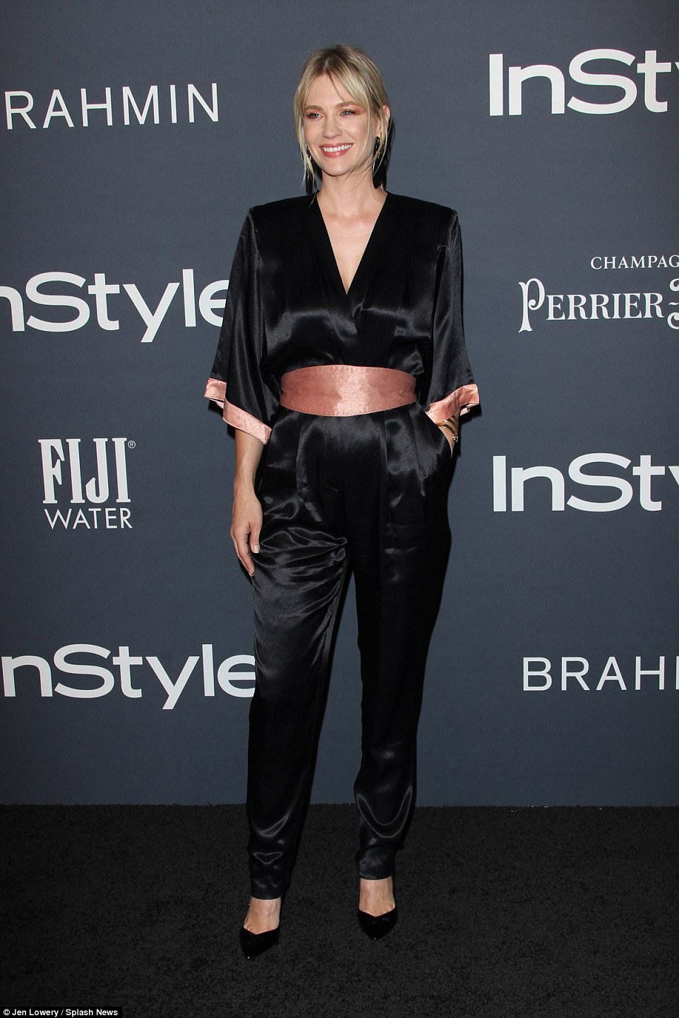 Blonde beauty: January Jones, 39, was sleekly styled in a black satin jumpsuit with a pink band at the waist and pink cuffs on the half sleeves. She added a pair of black pointed toe heels