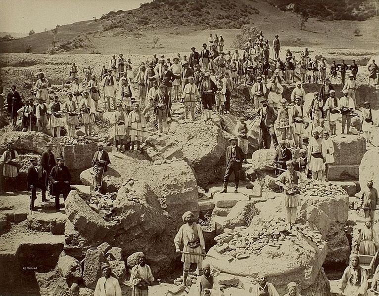 East side of the Zeus temple in Olympia — northern half to northeastern corner — with excavation crew. In front of the building there are statue bases.Date: 1875/1876