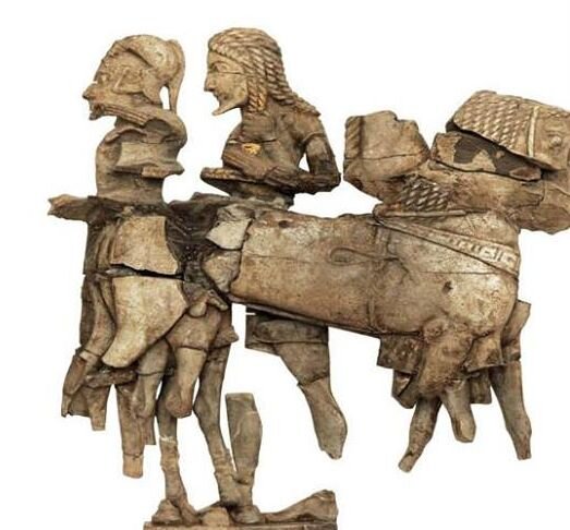 Two warriors in front of their chariot. One is trying to put on his helmet and the other is putting down his hair. 570 B.C.