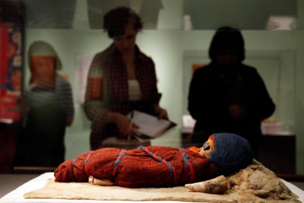 Members of the media view an infant mummy discovered in...
