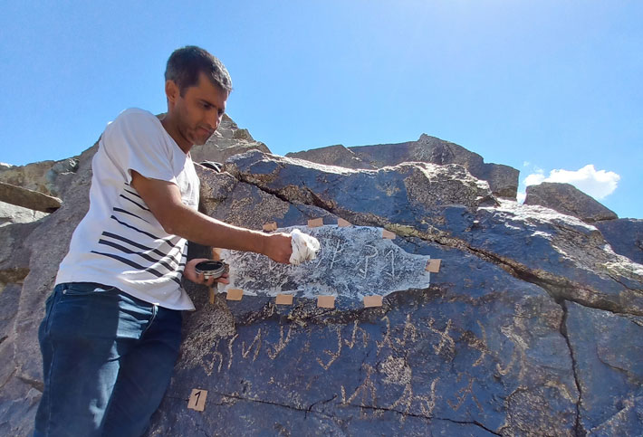 Archaeologist Bobomullo Bobomulloev uses the “squeeze” field method to record the inscription by applying and then brushing damp paper over the incised characters. The paper is then allowed to dry.