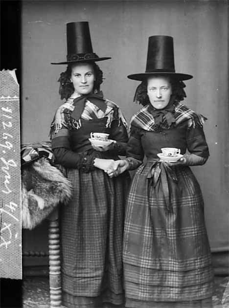 Two women in national dress drinking tea (Jones) NLW3362597, photograph by John Thomas, Wales. (Public Domain)